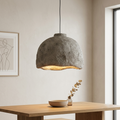 A pendant light unit with a design that mimics irregular natural stone formations, highlighting the aesthetics of the raw texture and adding a warm geological character to the architectural space.