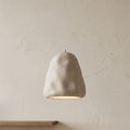 A pendant light with an irregular, streamlined design that mimics handcrafted clay formations, with a matte finish that provides soft lighting and brings tranquility and simplicity to the space.