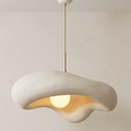 A pendant light unit with a streamlined sculptural design inspired by natural shapes such as seashells, combining a matte ceramic texture and warm lighting to give a calming character to the architectural space.