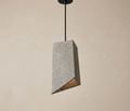 A pendant ceiling light with an asymmetrical geometric design and a sharp angle cut from raw concrete, reflecting the aesthetics of the modern industrial style with a simple architectural touch.