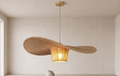A hanging light fixture made of natural braided fabric with a wide, flowing design, reflects warm shadows and adds a bohemian, nature-inspired character to the architectural space.